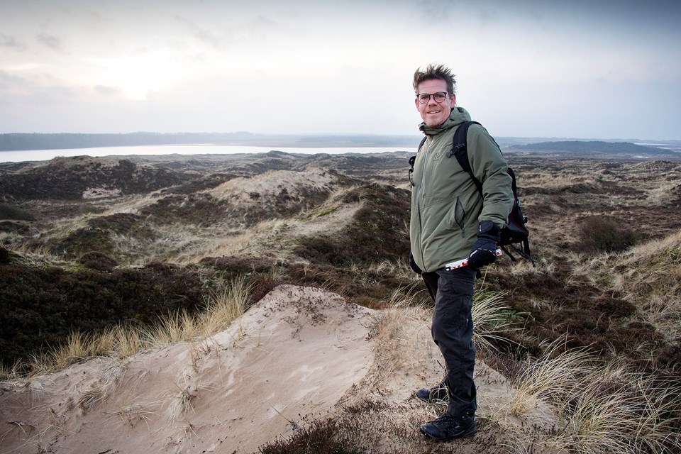 - Det var ikke det fedeste i verden, da nyheden kom om, at der var fundet en ulv i Thy. Den spiser mine dyr og mine børn, tænkte jeg. Men jeg var ikke så klog dengang, fortæller Thomas Boesdal. Her er han i Hanstholm Vildtreservat tæt på det sted, hvor den første ulv blev fundet død i 2012. Det er Nors Sø i baggrunden. Lone Lærke Krog og Peter Mørk (foto)